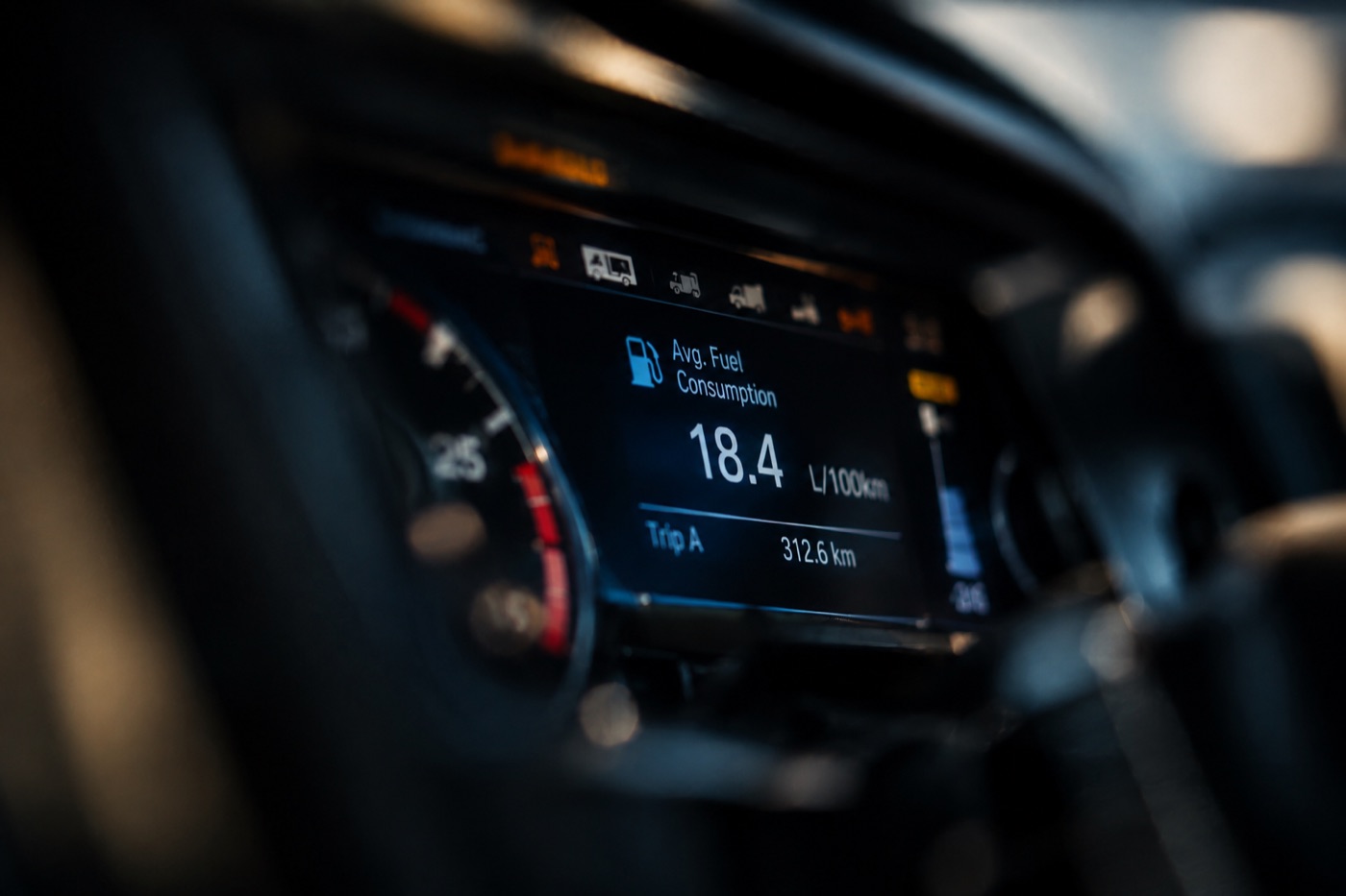 Truck dashboard fuel economy screen reading 18.4 litres per 100 km, with the trip meter at 312.6 km.