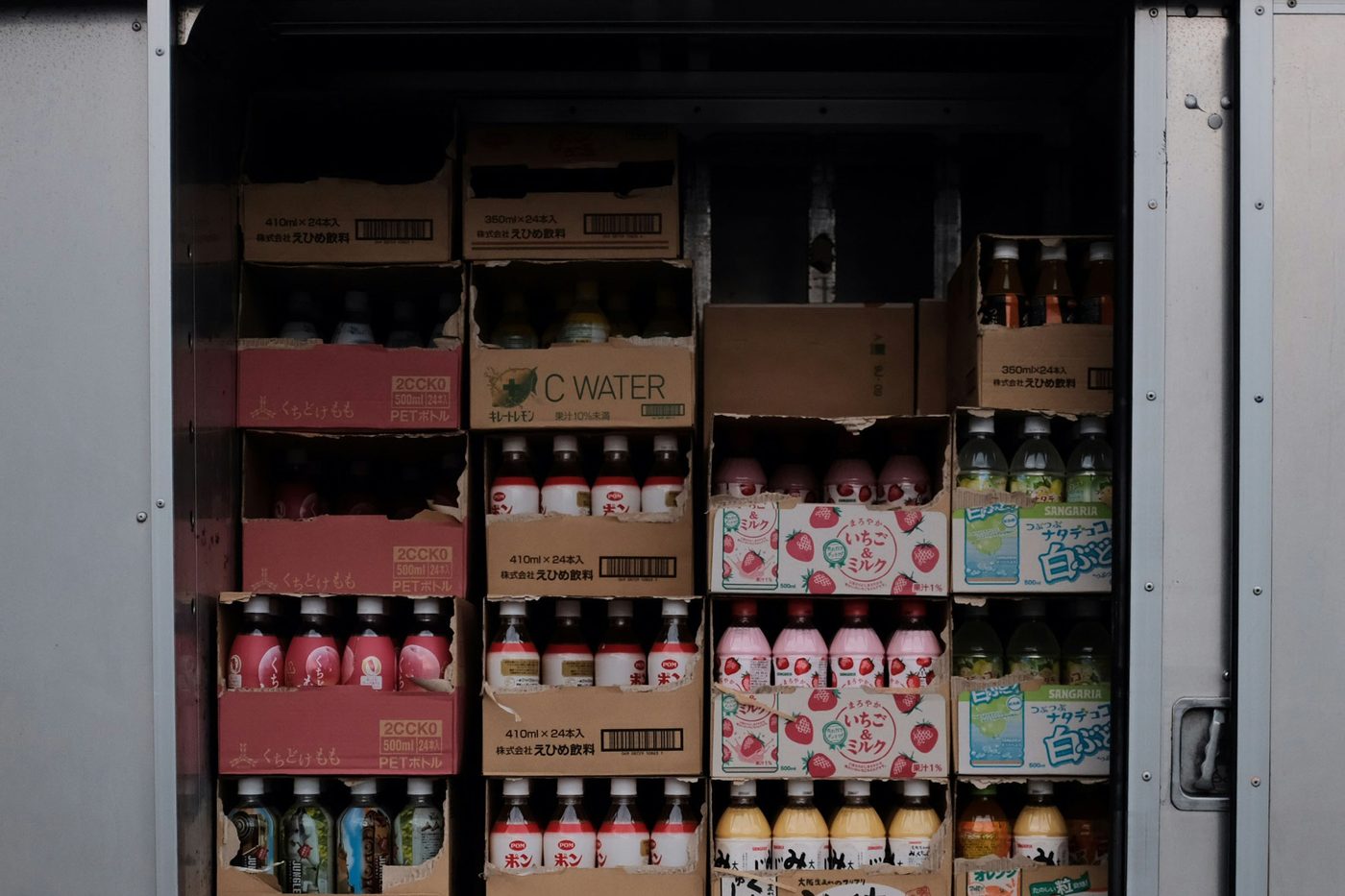 Cartons of bottled drinks stacked from floor to roof in the open side door of a delivery truck.